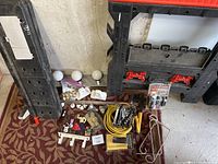 Overview of lot showing foldable sawhorses, vanity lights, light bulbs, tools, wiring, and door hardware.