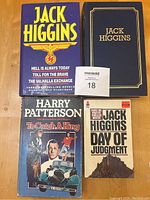 Top view of four books including Jack Higgins novels in a blue slipcase, one with purple dust jacket, Harry Patterson and a softcover Jack Higgins.