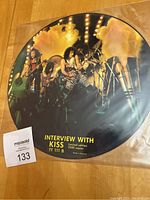 Front view of KISS limited edition interview picture disc showing the band on stage with lights and smoke, with text indicating limited run of 2500 copies.