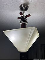 Pendant chandelier hanging from ceiling with geometric frosted glass shade and dark metal accents.