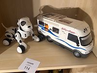 The Hymer white camper RV and black and white Dalmatian electronic toy dog placed on a wooden surface with good view of both items together.