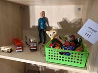 Overall lot showing Tonka horse hauling truck, two horse pulling vehicles, a tall figurine, and a green basket filled with small toys including a cat figurine