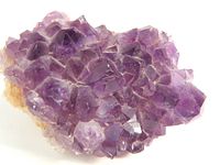 Close up of purple amethyst crystal cluster showcasing the crystalline structure and color variation.