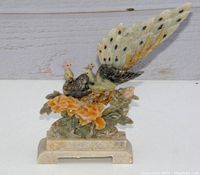 Front and side view of the carved soapstone peacock figurine showing detailed coloring and floral base.
