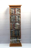 Full front view of a tall wood CD cabinet wrapped in plastic, filled with CDs.