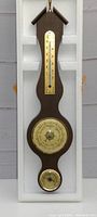 Front view of entire barometer including thermometer and dials in wooden case with foam padding.