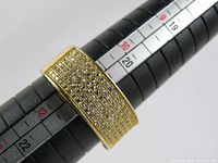 Top view showing the rectangular face of the sygnet ring fully set with multiple rows of small clear stones, gold-tone band resting on ring sizing mandrel showing size 11