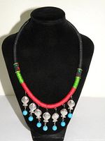 Full frontal view of the bohemian tribal necklace displayed on a black bust stand showing wrapped cord sections and fish charms with turquoise beads.