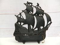 Front side view of the vintage cast iron ship lamp showing detailed sails and hull decorations with pull chain on base.
