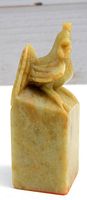 Side view of the jade seal showing detail of the hen figurine on top and color variations of the jade stone.