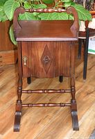 Front view of the vintage wooden humidor smoking stand showing carved details, turned legs and top surface with back rail.