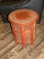 Full view of the vintage teak wood foldable circular teapoy showing carved lattice side panels and ornate top.