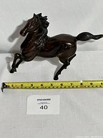 Side view of bronze horse statue with measuring tape showing about 10 inch length, showing detail and surface condition including few paint nicks.