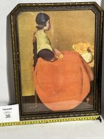 Full view of framed print showing a woman in an orange skirt seated in profile with a flower vase in background.