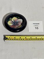 Side and angled top view showing overall shape and size of pottery dish with measuring tape and auction lot card.