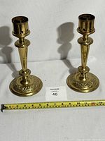 Pair of brass church altar candlestick holders with measuring tape showing approximate height of 10 inches each