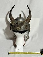 Full front view of helmet on white display head showing horns, eagle motif and measuring tape