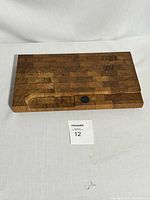 Top angled view showing rectangular solid teak cutting board with magnetic circular holder and carved groove.