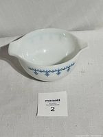 Full overhead view of the white glass Pyrex Cinderella nesting bowl with blue snowflake garland design, showing shape and decoration.