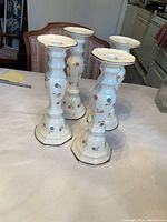 Four white ceramic Japanese candlesticks with floral patterns, two pairs.