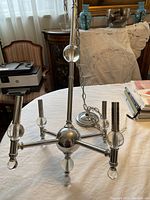 Full view of the chandelier placed on a table showing its structure, chrome finish, and crystal ball accents.