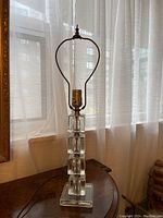 Full view of the vintage crystal table lamp showing the stacked block pattern base and metal socket.