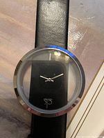 Close-up of round watch face showing black dial with silver hands and Calvin Klein logo