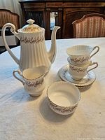 Photo showing entire coffee set with pot, creamer, sugar bowl, two cups and two saucers on table, highlighting pattern and condition.