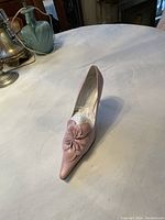 Single pink women's leather shoe with floral leather detail on toe, placed on table.