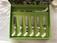 Cheese knife and six spreaders inside lime green box with floral patterned handles