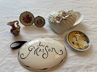 Lot showing three small Limoges pieces including a miniature jug and two floral plaques behind, a heart-shaped trinket dish with floral lid, a La Maison ceramic sign, and a small Asian decorative plate.