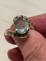 Close-up photo of the sterling silver ring on finger showing large blue stone and marcasite decoration