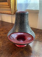 Front angle view of the MCM tealight holder showing textured black exterior and red interior opening for candle placement.