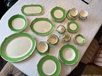 Full set of green-bordered dishes, platters and bowl arranged on table