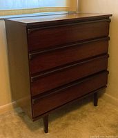 Photo showing a mid-century modern 4-drawer wooden dresser with a dark wood finish, tapered legs, and recessed drawer pulls. The finish shows some wear and damage.