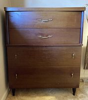 Front view of the mid-century modern 4-drawer dresser showing all drawers and metal and wood handles.