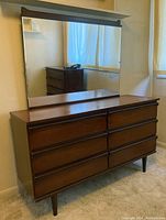 Full front view of the 6-drawer wooden dresser with large mirror mounted on back.