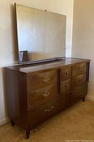 Full view of vintage wooden dresser with attached large rectangular mirror showing mid-century design and drawer arrangement.