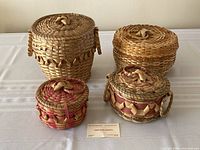 Four handmade baskets of varying sizes and weave patterns on white cloth