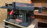 Side view of Craftsman table saw showing red adjustment handle, blade guard, and motor specs on label