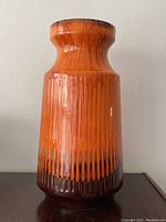 Front view of tall orange mid-century modern ceramic vase with a textured vertical drip glaze pattern transitioning from orange to brown near the base and rim.