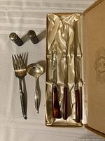 All items arranged together on cream satin fabric inside box for display: 3-piece stainless steel carving set, Wm Rogers gravy ladle and meat fork, silver-plated salt and pepper shakers with cobalt blue glass inserts.