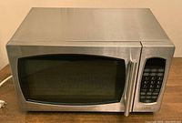 Front view of Salton microwave oven showing brushed stainless steel exterior, door with viewing window, and numeric keypad control panel on the right side.