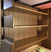 Photo showing three of the five wooden shelves stacked, highlighting vertical end pieces and wood veneer finish.