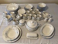 Full overview of the dining set showing plates, bowls, cups, mugs, platters, and serving pieces arranged on a table.