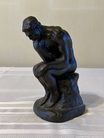Front view of bronze-coated sculpture of Rodin's The Thinker with detailed pose and texture