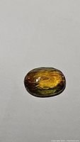 Top view of oval cut African sphene gemstone showing rich golden to greenish color and faceting