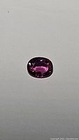Oval hot pink purple sapphire gemstone on neutral background