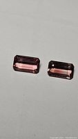 Photo of two octagon cut pink tourmaline gemstones lying on a flat surface, showing clarity, color, and cuts.