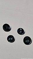 Close-up photo of four round cut blue sapphire gemstones showing their deep blue color and round faceted shape.